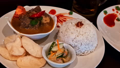 indonesian beef curry served with steamed rice and garnished with herbs and chili