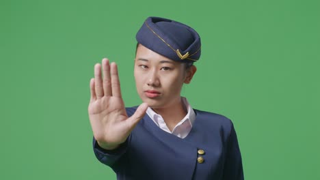 녹색 스크린 배경 스튜디오에서 손 표시 없이 카메라를 바라보며 불쾌감을 표하는 아시아 여성 승무원의 클로즈업