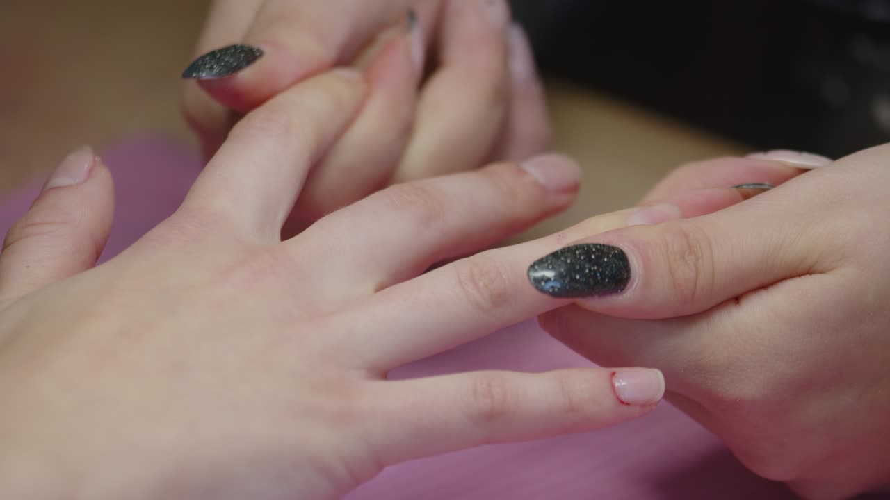 Manicurist masserer kvindes fingre i negleklinik