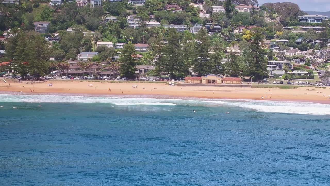 Aerial reveal of surfers bobbing about in the water at Palm Beach in Sydney
