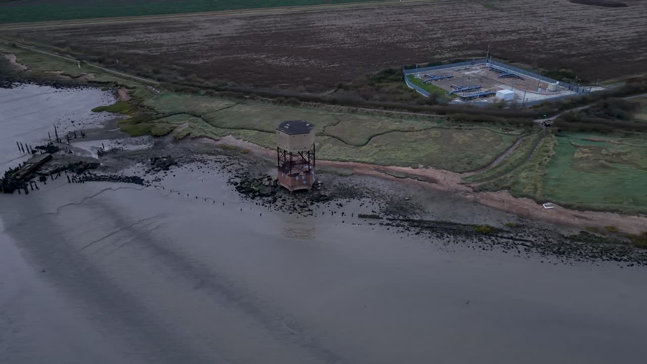 Aerial view circling over East Tilbury abandoned radar tower on the River Thames foreshore marshland