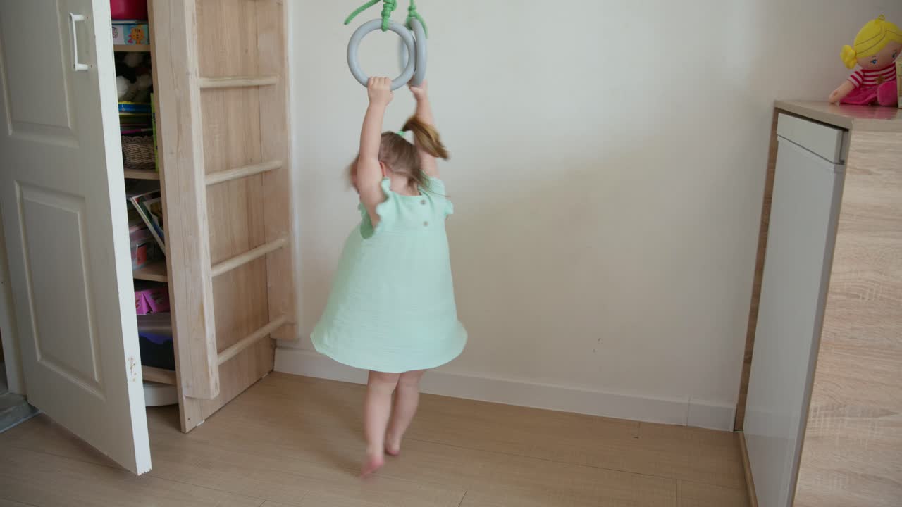 Little Girl Playing on Gymnastic Rings in Her Room