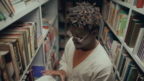 young black man selecting book for reading or study in library