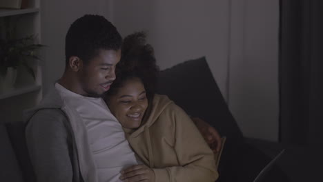 young couple laughing while watching a film on the laptop