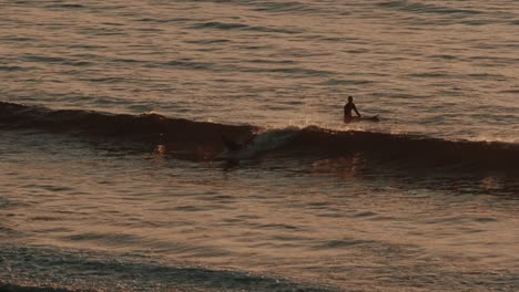 two surfers in the water during sunset in slow motion