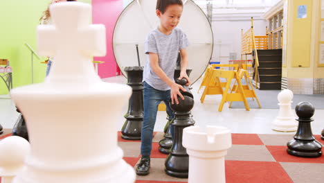 niños de la escuela jugando al ajedrez gigante en un centro de actividades científicas