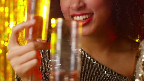 close up of two women in nightclub or bar celebrating drinking alcohol with sparkling lights 3