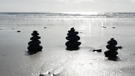 rock balancing on ocean beach, stones stacking by sea water waves. pyramid of pebbles on sandy shore