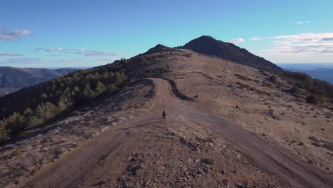 aerial shot back view of young hiker in mountain range close to madrid during afternoon with blue sky and white clouds