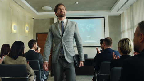 caucasian male business speaker finishing his conference in a meeting and going away cheerfully while people clapping