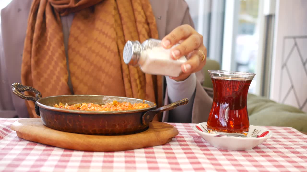 Çay ve menemen ile geleneksel Türk kahvaltısı yapan kadın