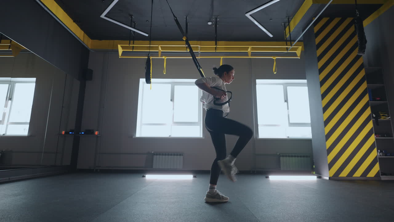 haciendo ejercicios trx. joven mujer atlética en ropa deportiva entrenando piernas con correas de fitness trx en el gimnasio. ejercicio donde estabilizar los músculos entrenados y todo el cuerpo está trabajando verdaderamente funcional
