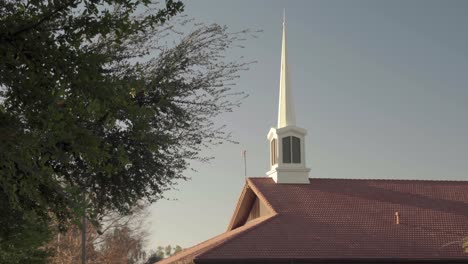 Dach-Der-Mormonenkirche-Mit-Turmspitze-Bei-Sonnenaufgang-Äste-Im-Vordergrund-4k