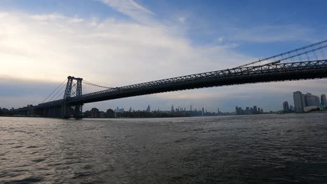 boat crossing under large bridge in manhattan new york