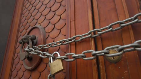 Ornate-wooden-Roman-door,-with-chain-through-door-knockers