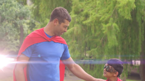 animación de luces sobre padre y hijo caucásicos felices divirtiéndose vestidos como superhéroes