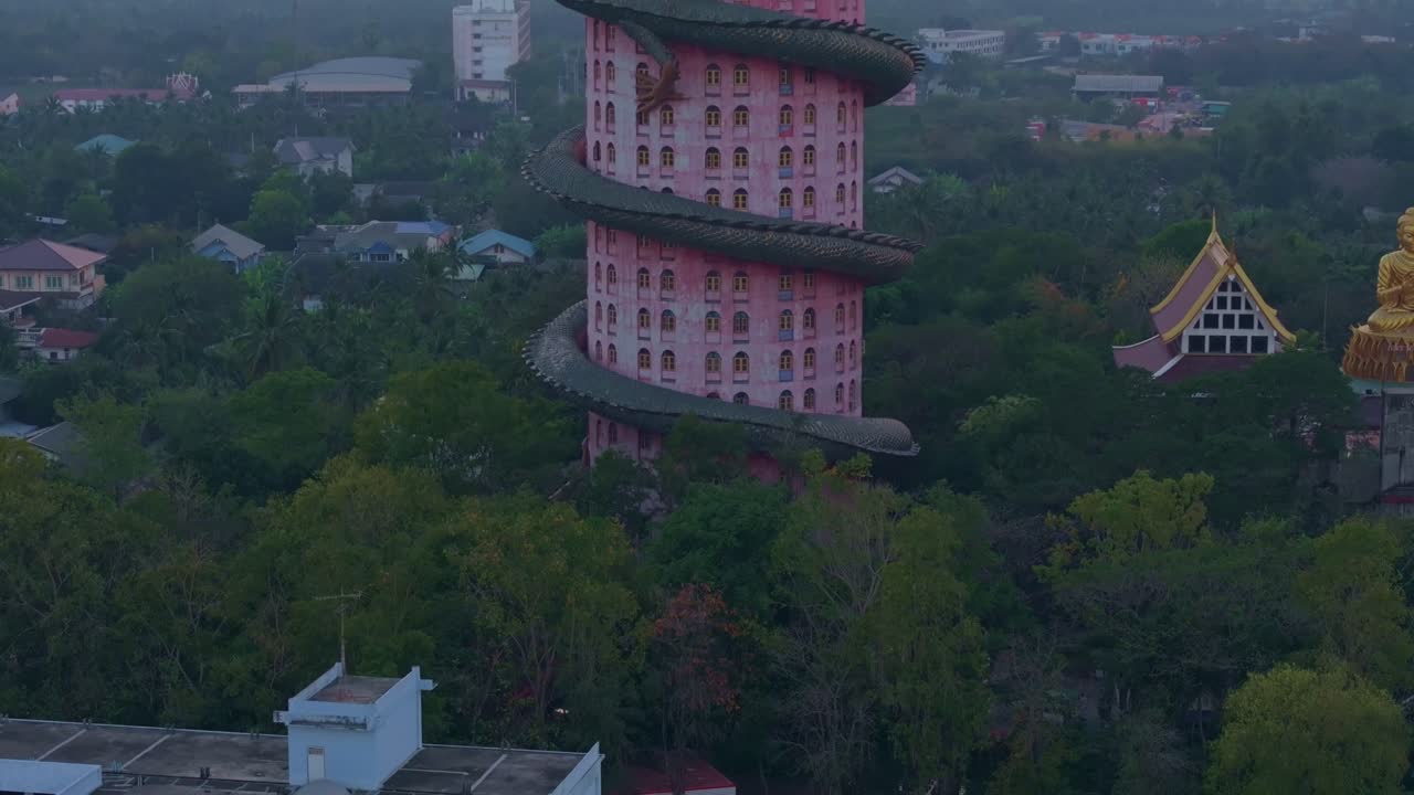 Toma de dron del templo del dragón Wat Sam Phran brillando con la luz del atardecer, Tailandia