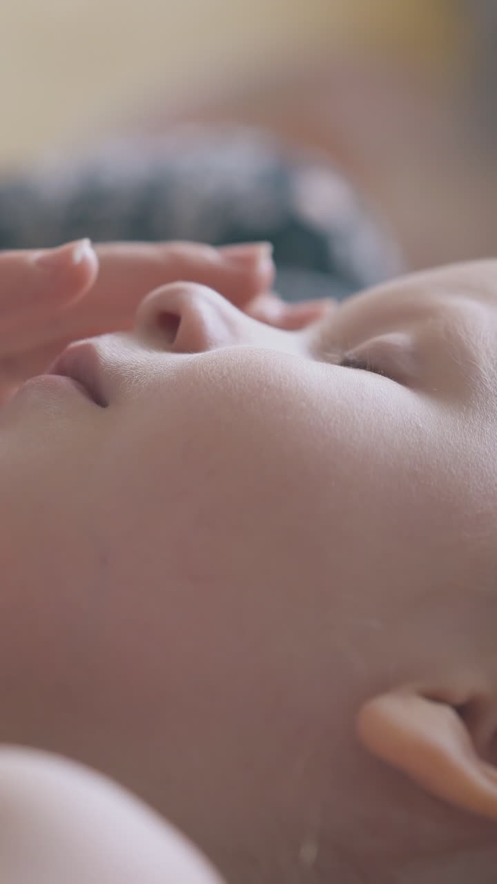 careful mommy massages nose and forehead of little sick girl on bed in light room extreme close view