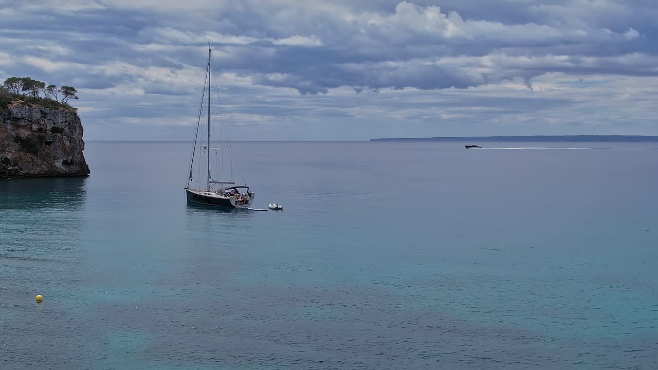 Sailboat anchored near coastline in Mallorca, Spain during cloudy day