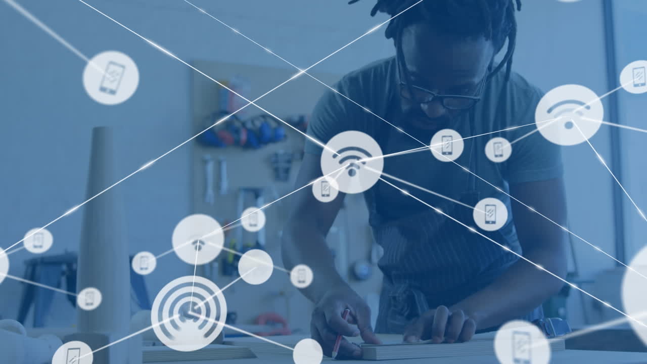 Animation of network of wifi icons over african american male craftsman working in studio