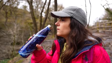 Woman drinks from a metal bottle while hiking in Brecon Beacons National Park, Wales