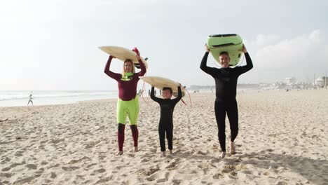 family of surfers walking on beach