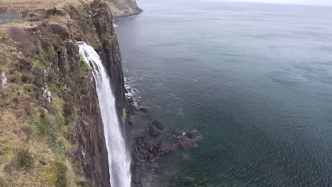 Tilt-up-shot-of-Mealt-Waterfall,-the-cliffs-and-Atlantic-Ocean-on-a-cloudy-day-in-Scotland,-isle-of-Skye