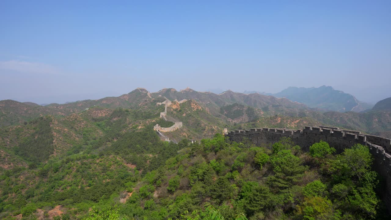 Panoramablick auf die Chinesische Mauer, die sich durch üppige Berge im Abschnitt Jinshanling schlängelt.