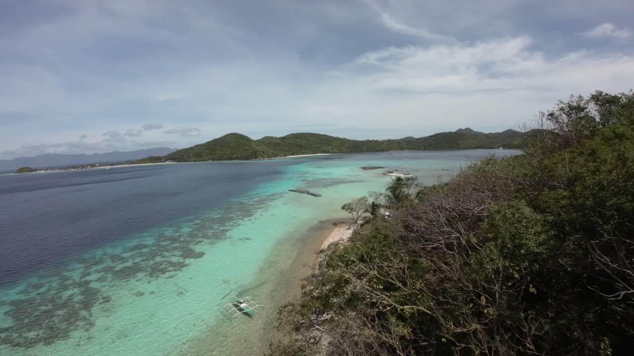 Ripresa da drone FPV sopra acqua turchese su una costa tropicale a Coron, Filippine.