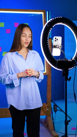 creator readies for video shoot. a woman stands by a ring light in a colorful studio, ready to film among sticky notes and her gear