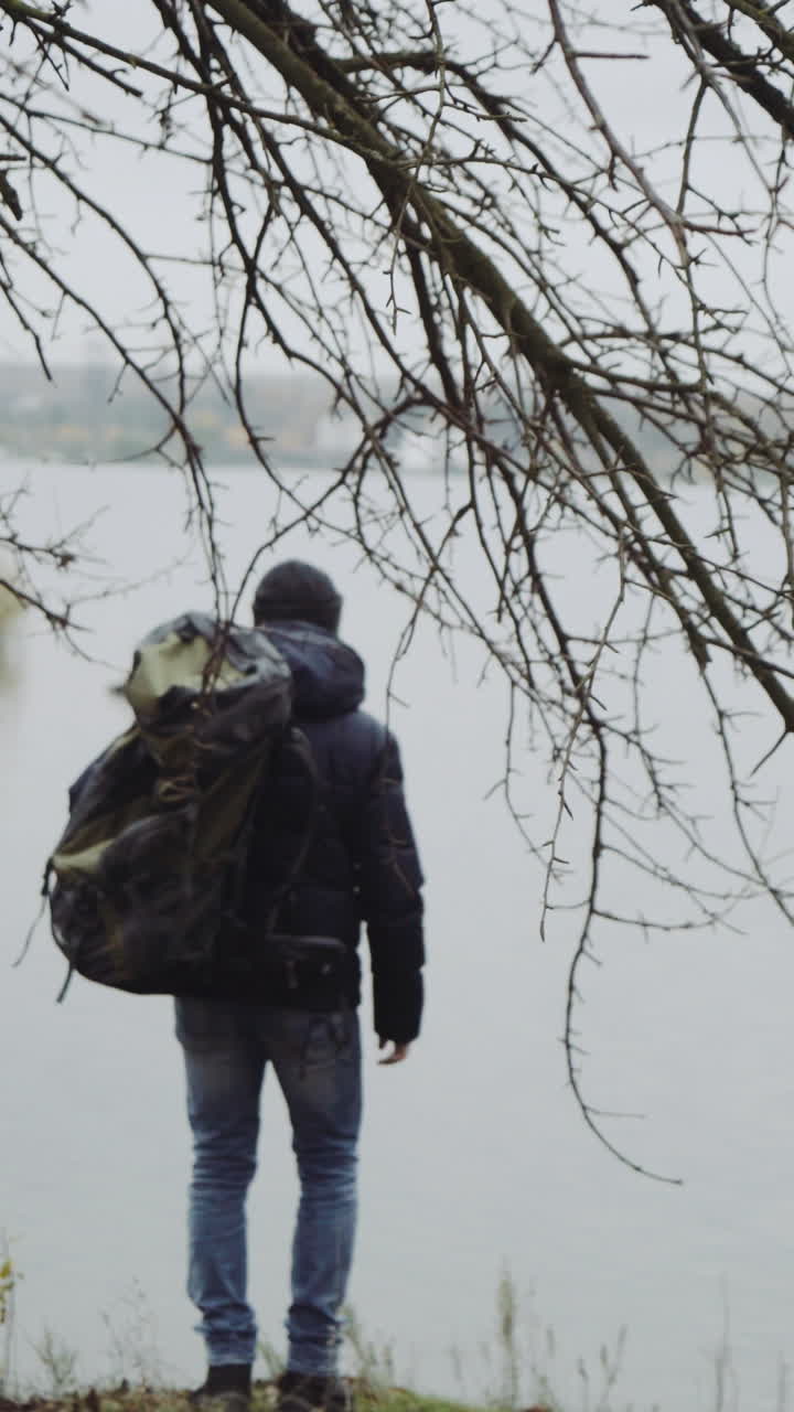 Tourist man enjoy nature. Traveler with backpack relaxing near river in forest