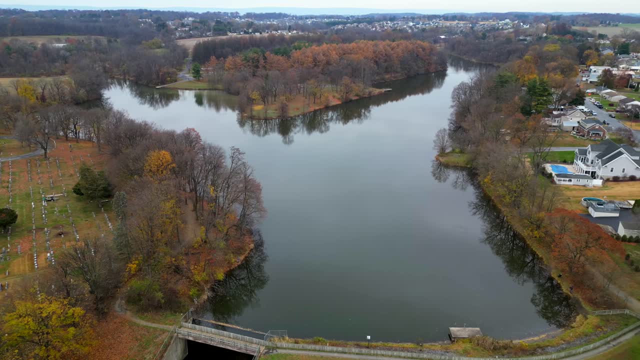 Aerial drone video of a lake and dam. Next to a cemetery during fall