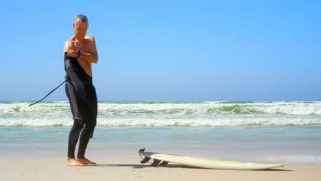 Seitenansicht-Eines-Aktiven-älteren-Kaukasischen-Männlichen-Surfers-Im-Neoprenanzug-Am-Strand-4k