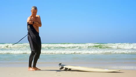 side view of active senior caucasian male surfer wearing wet suit on the beach 4k
