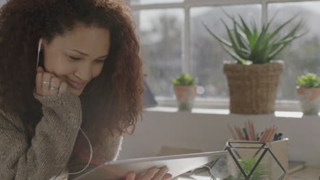 young mixed race woman using tablet watching video smiling enjoying entertainment listening to music wearing earphones in vibrant home