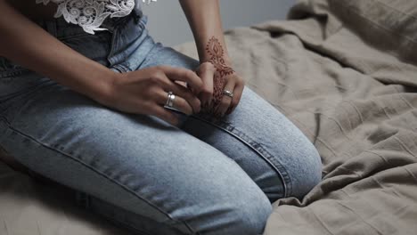 woman with henna tattoo on her hand sitting on a bed