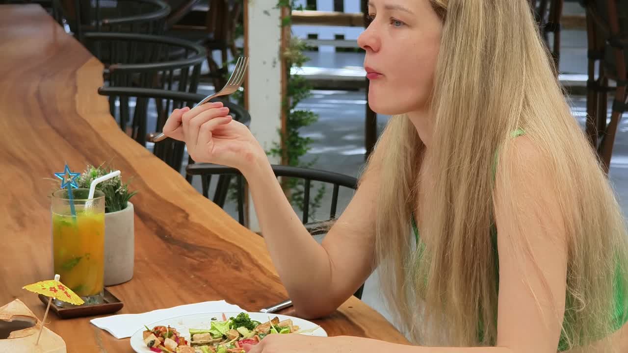 mujer disfrutando de un almuerzo saludable en un café tropical al aire libre