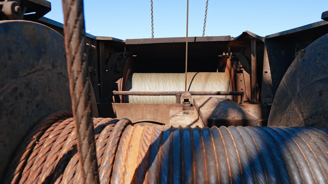 Two rollers with thick metal wires winding. Equipment working at the site producing oil, gas or other natural resources.