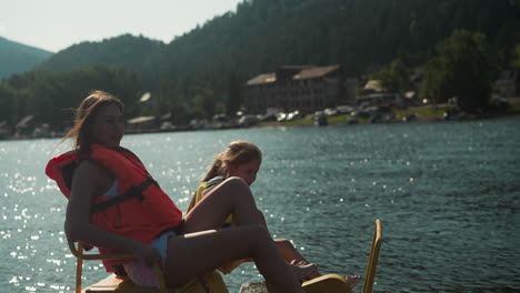 madre e hija disfrutan del movimiento en el lago. las hembras miran el pintoresco paisaje sentadas en catamarán en cámara lenta. los turistas viajan en transporte acuático en un día soleado vista lateral