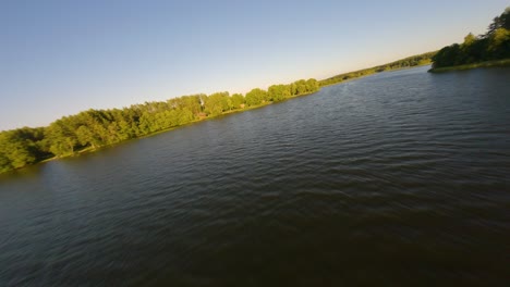 Drone-flight-approaching-the-shoreline-of-lake-Baluosas-in-Lithuania-during-sunset