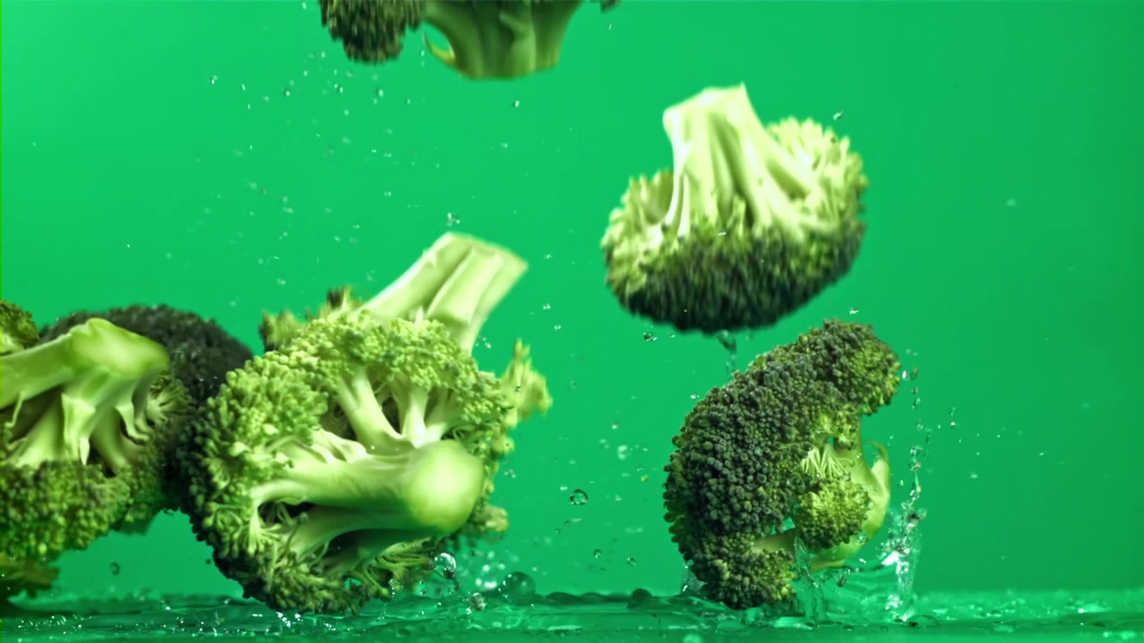 Cimette di broccoli freschi che cadono e schizzano su una superficie verde bagnata