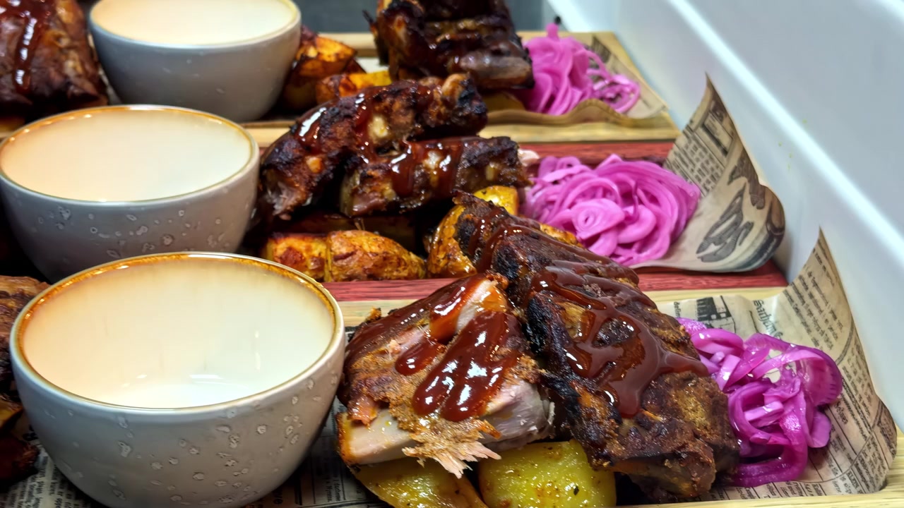 Chef prepara costillas a la barbacoa con patatas, salsas y cebollas encurtidas en fuentes