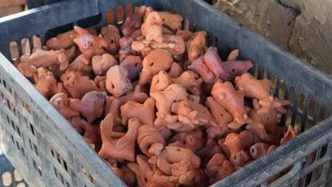 gloved hand adjust placement of clay figurines in crate, than ha hoi an vietnam