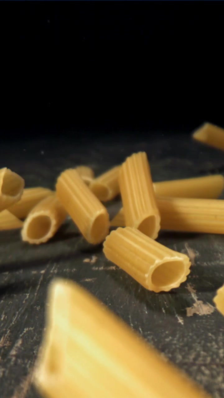 Penne che cadono al rallentatore su una superficie scura