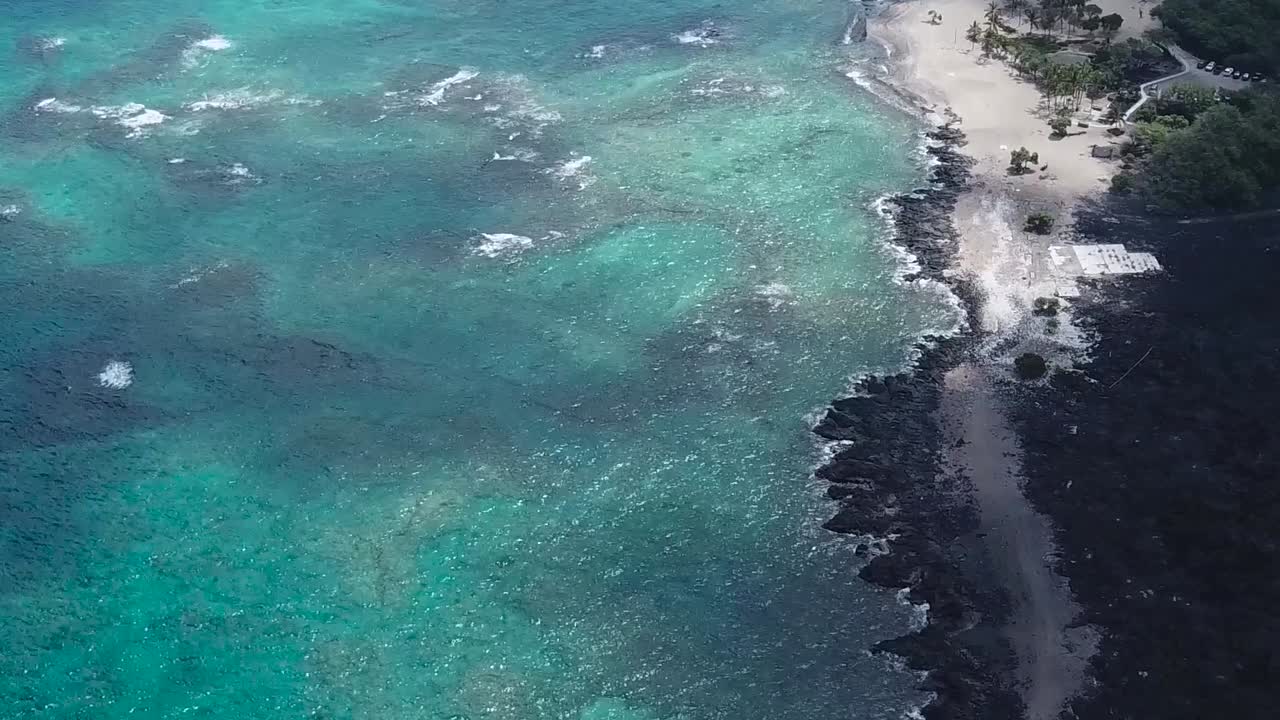 Ripresa aerea con drone: spiaggia di sabbia nera, panoramica verso il basso su acqua blu.