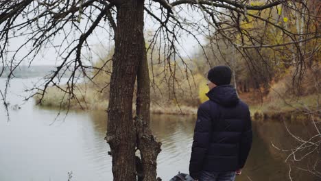 backpacker tourist near river. traveler man standing near river and enjoying view of riverscape