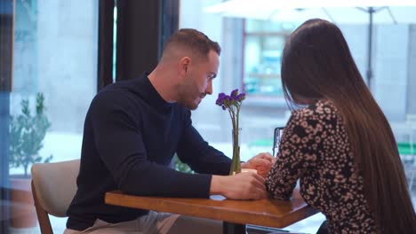 content couple watching video on smartphone in cafe