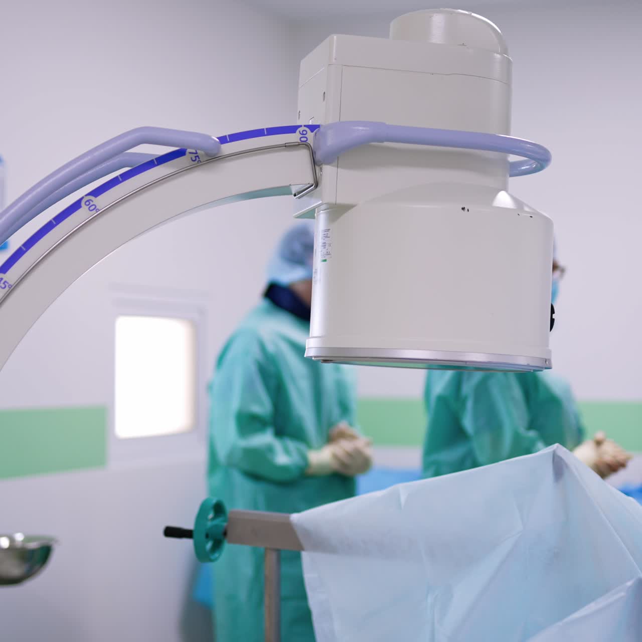 C-Arm x-ray machine standing over the patient in surgery room. Surgeon study x-ray scans near the screen