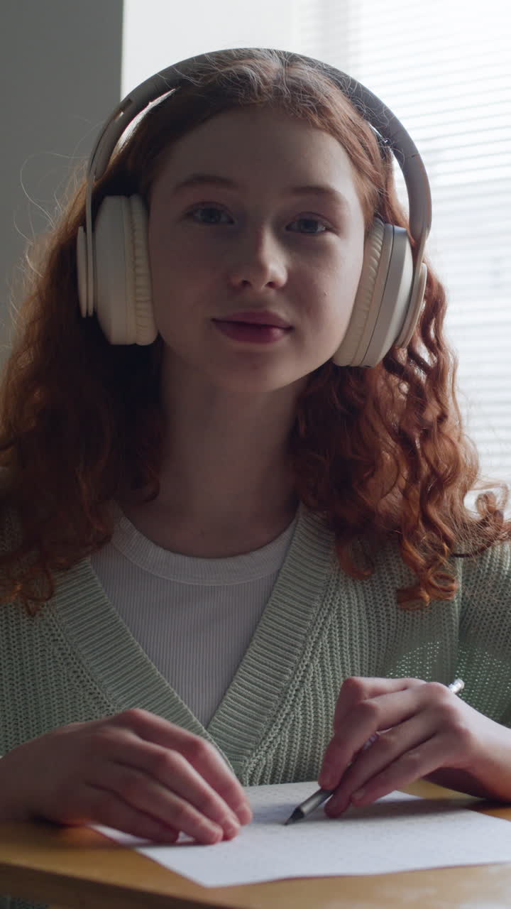 una adolescente estudiando con auriculares