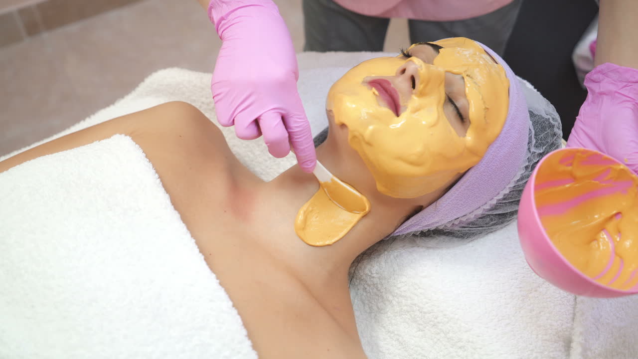 Estetista che applica una maschera viso in un salone di bellezza. Cura della pelle. Trattamento di bellezza. Bella donna con maschera viso in un salone di bellezza